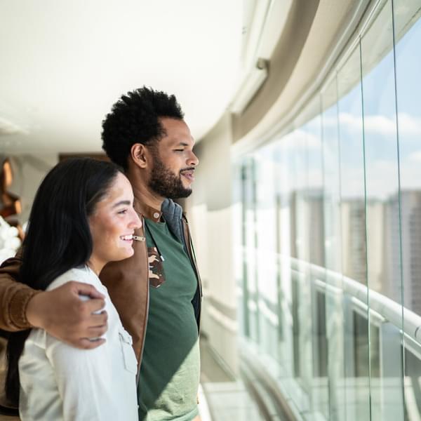 Young happy couple enjoying while looking through window in a hallway.