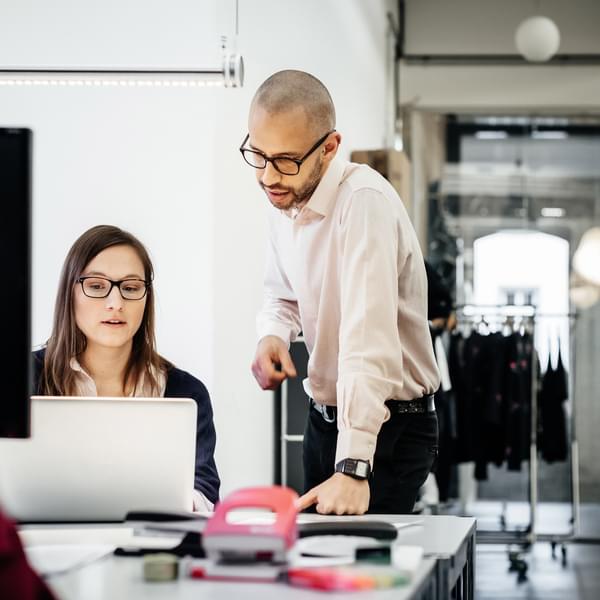 Two businesspeople working on a laptop in an office