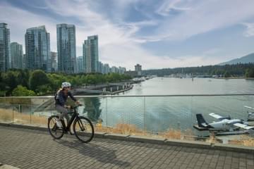 A woman riding an ebike through the city with views of downtown city skyline.