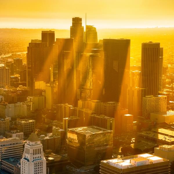 The downtown buildings of Los Angeles, California, silhouetted by the sunset with rays of sun reflecting off the haze