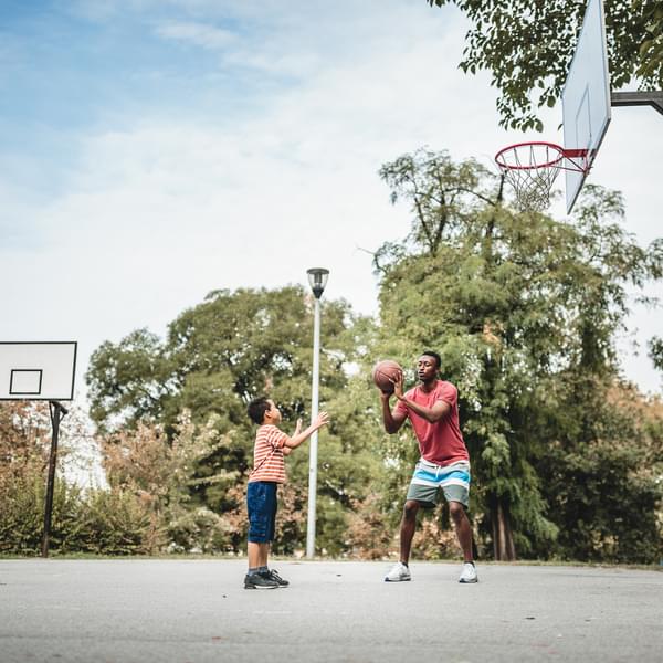 Father and son playing basketball outside.