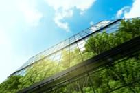 Image of business building with reflection of green trees and blue sky.