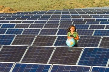 Native American girl standing near solar panels holding globe.