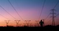 Silhouette of person thinking and looking at electric power lines at sunset.