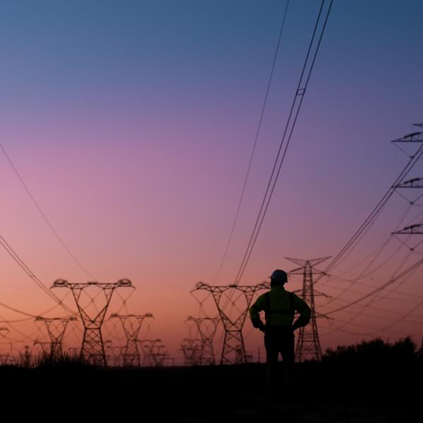Silhouette of person thinking and looking at electric power lines at sunset.