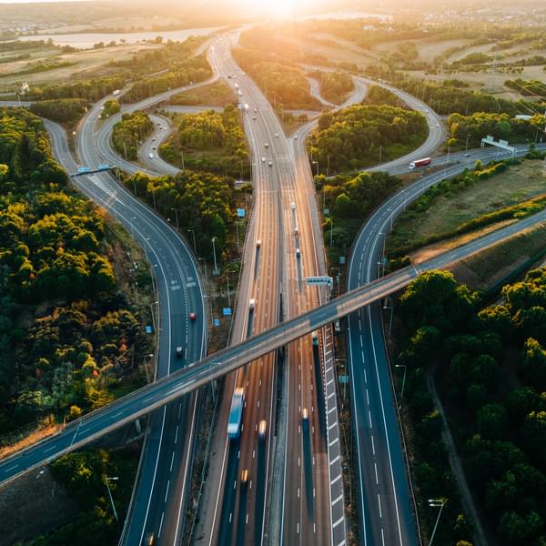 Aerial of busy highways intersecting with fast cars and electric vehicles on roads