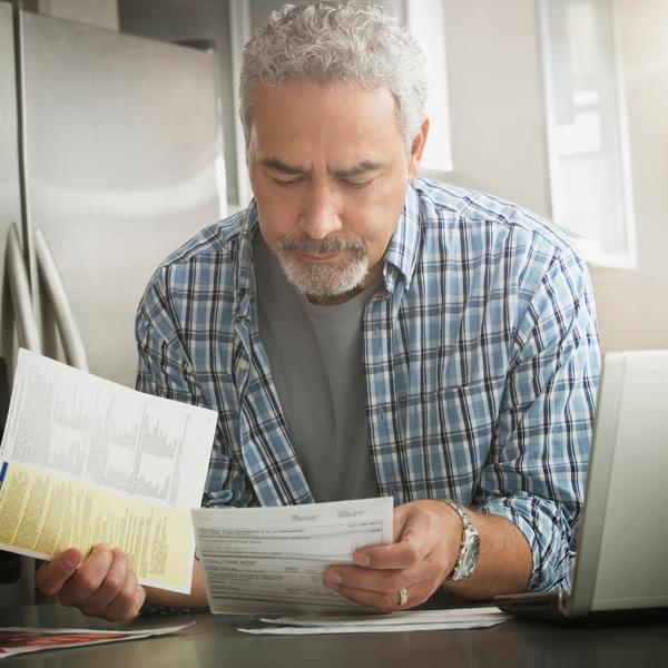 Hispanic man paying bills on laptop in kitchen