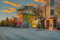 The morning sun shines intently on the facades of small businesses on this street.