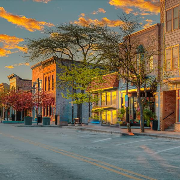 The morning sun shines intently on the facades of small businesses on this street.
