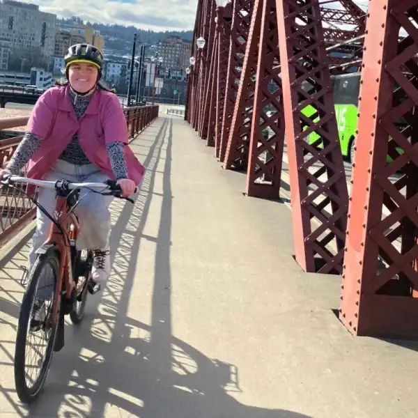 View of a city commuter riding to work on a bicycle. Young woman traveling on a bike, wearing a helmet for safety.