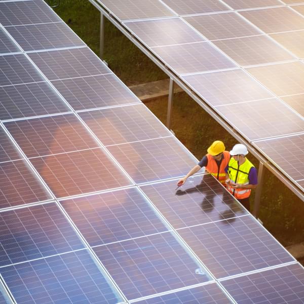 Aerial view solar energy team working at solar power station. Two technicians install solar panel at solar roof top.