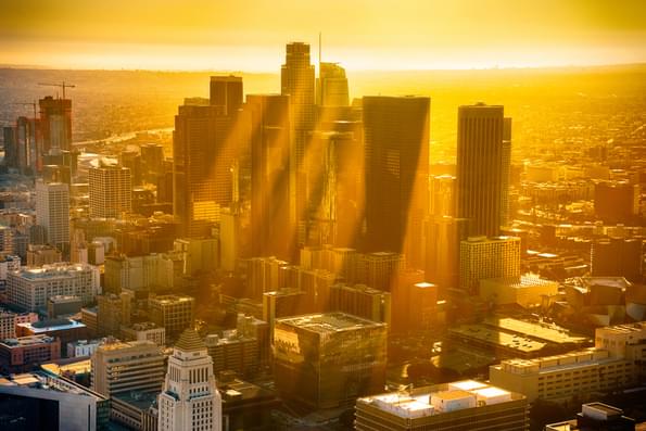 The downtown buildings of Los Angeles, California, silhouetted by the sunset with rays of sun reflecting off the haze