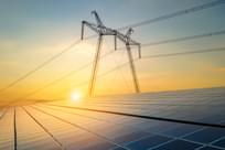 High voltage pylons with electric power lines transferring electricity from solar photovoltaic cells at sunrise.
