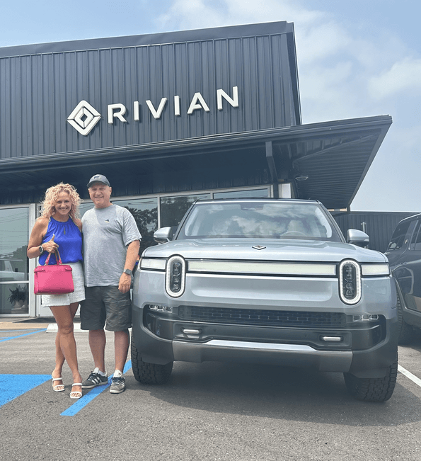 Resource Innovations employee posing in front of his electric vehicle