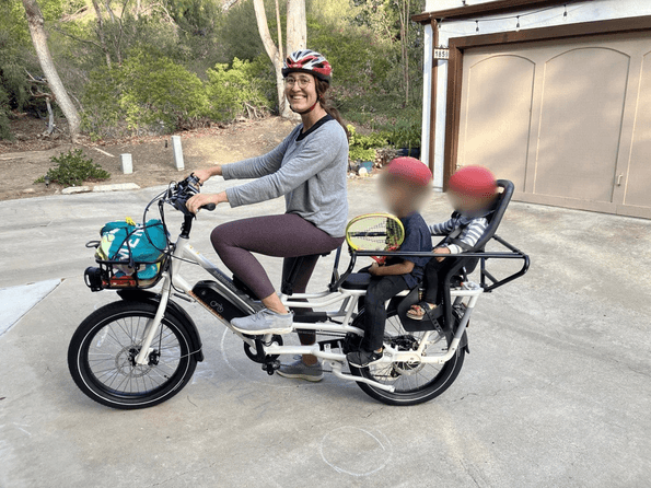 Resource Innovations employee riding her electric bicycle with two children