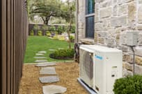 Daikin Fit Heat Pump next to home with view of yard