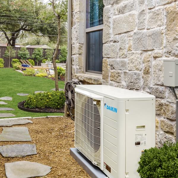 Daikin Fit Heat Pump next to home with view of yard