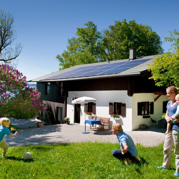 Family plays outside their home which has solar panels