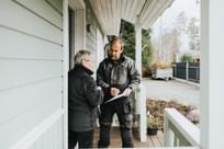 Contractor and homeowner on front porch going over instructions on a clipboard.
