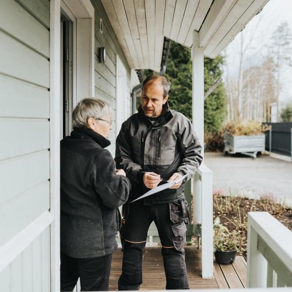 Contractor and homeowner on front porch going over instructions on a clipboard.
