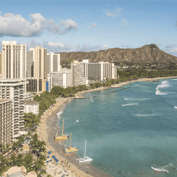 View of Waikiki beach and Honolulu cityscape with Diamond Head in the background on a sunny day.