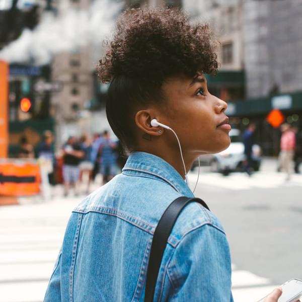 Young African American woman walking on the sidewalk in a metropolitan city looking optimistic.