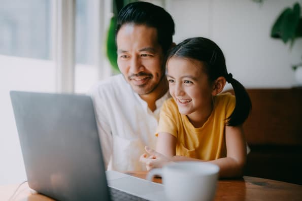 Dad and daughter in their home looking at a laptop
