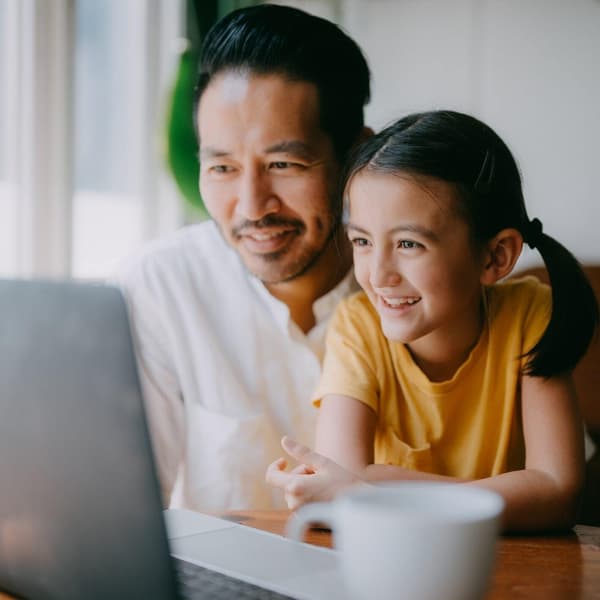 Dad and daughter in their home looking at a laptop
