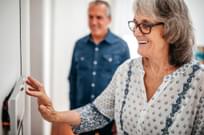 Senior woman using home automation touch screen panel in home