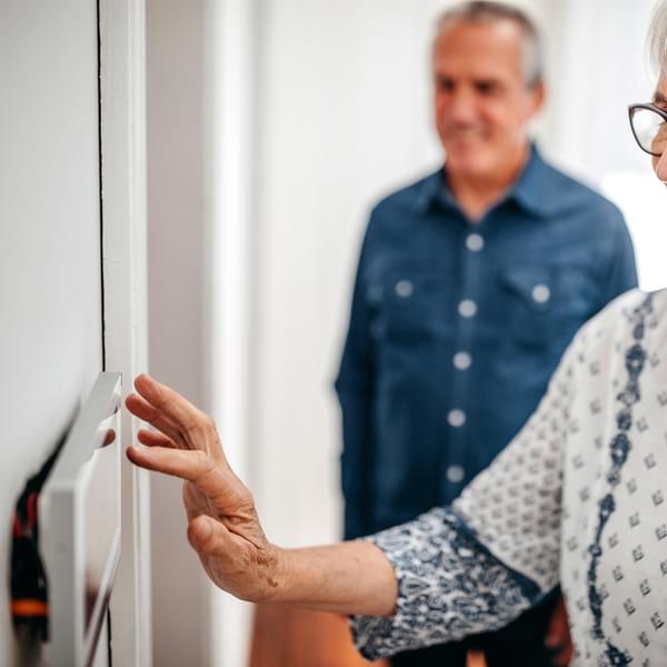 Senior woman using home automation touch screen panel in home