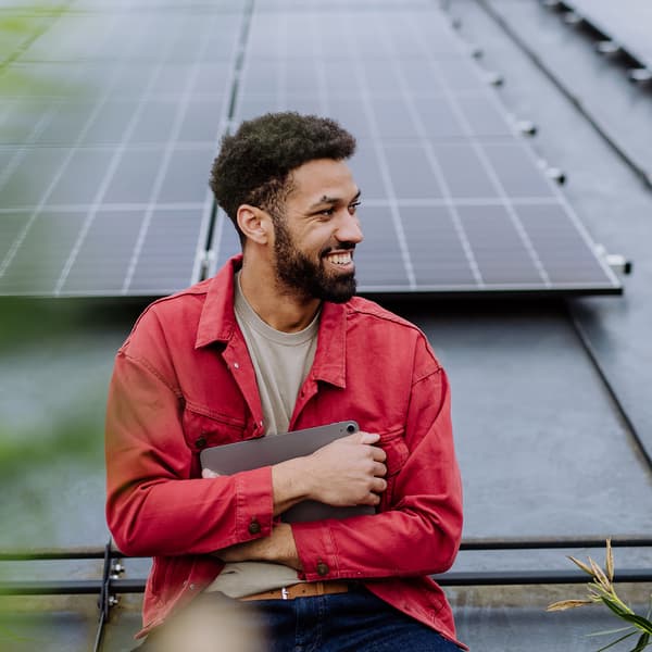 Smiling male engineer in front of photovoltaic (PV) cells or solar panels