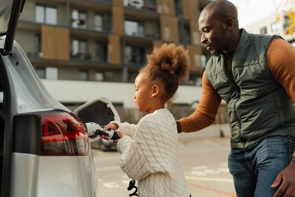 Father with his daughter charging their electric car