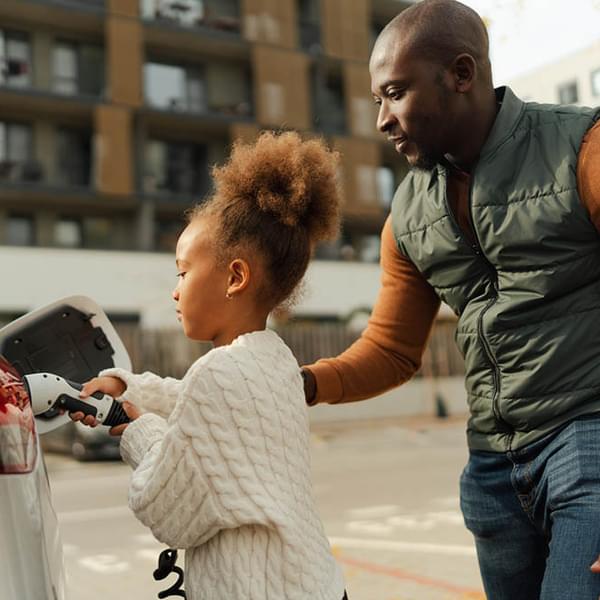 Father with his daughter charging their electric car