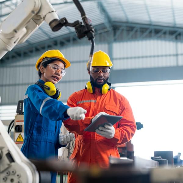 Female Quality Engineer and Male Production Engineer talking in a warehouse factory.