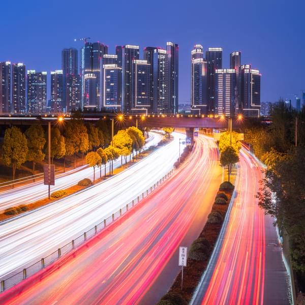 Skyline panorama at blue hour with car traffic light trails in the foreground.