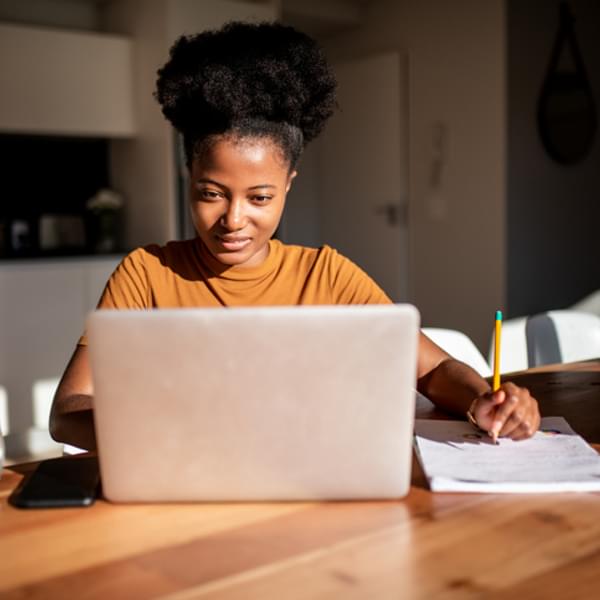 Young woman reading from the computer and taking notes at her notebook.