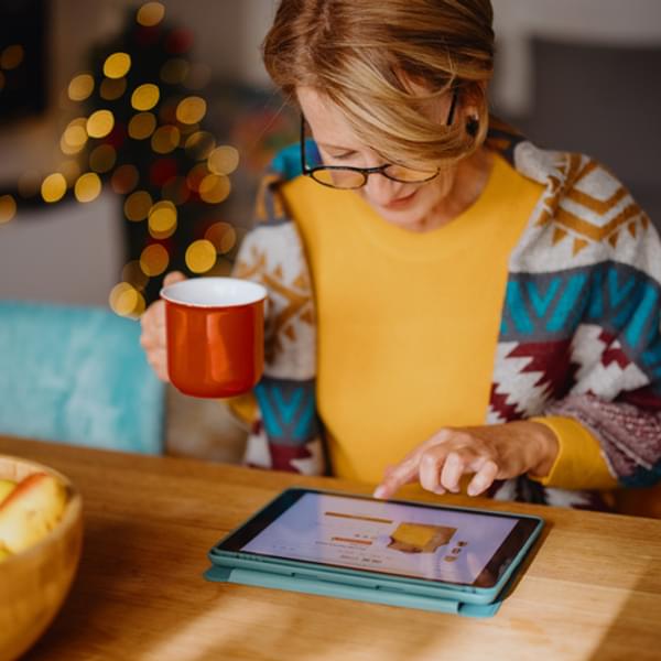Woman enjoying online shopping and using digital tablet and credit card while sitting at dining table