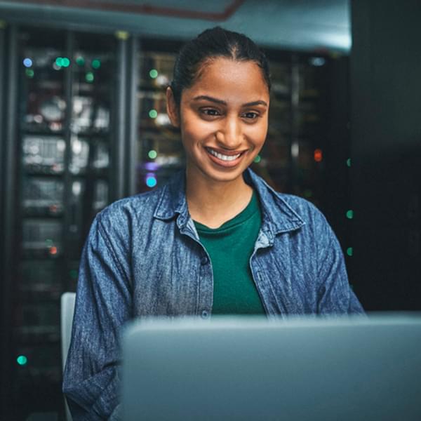 Shot of an female software professional in a server room and using a laptop