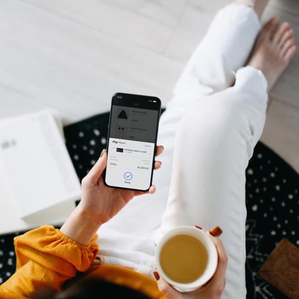 Overhead view of young Asian woman relaxing at home, shopping online with smartphone and making payment online with credit card.