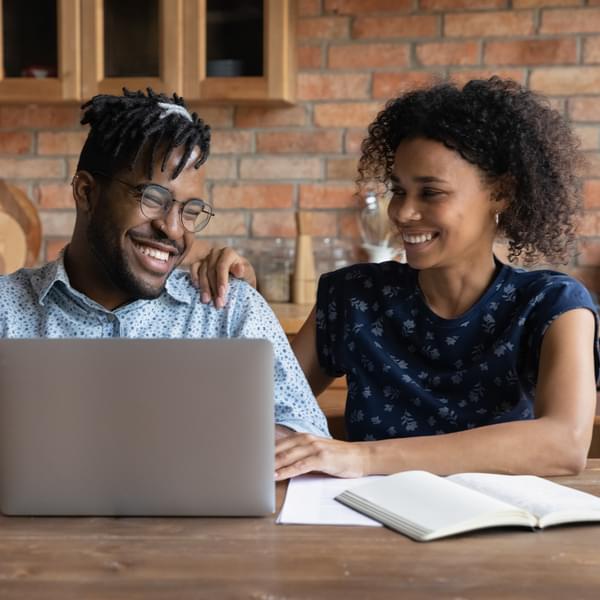 A man and woman joyfully look at their utility energy bills online.