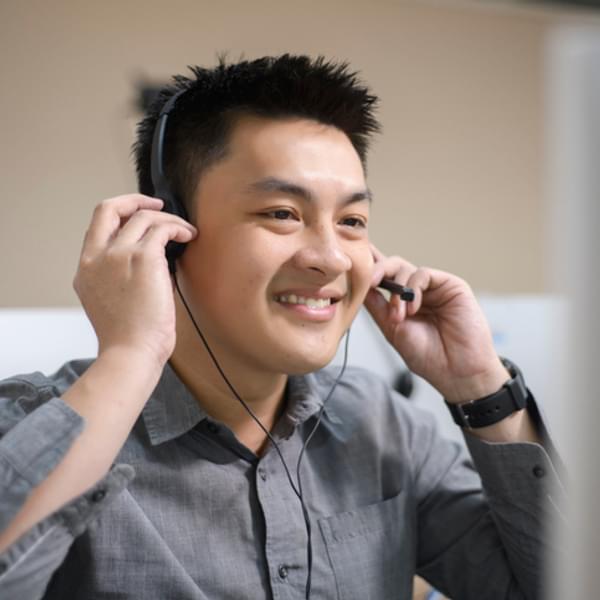 Smiling customer service representative using computer at desk.