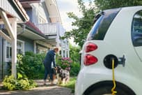 Woman walking to entrance of her house while her electric car is charging