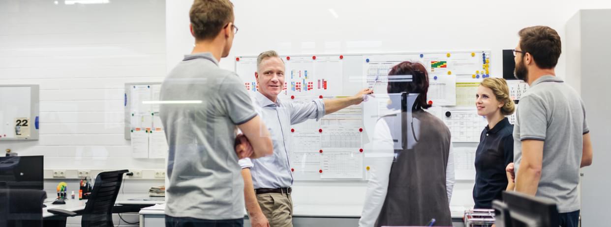 Manager meeting with engineers and staff in an industrial office space