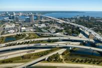 Aerial view of Jacksonville city with high office buildings and American freeway intersection with fast moving cars and trucks