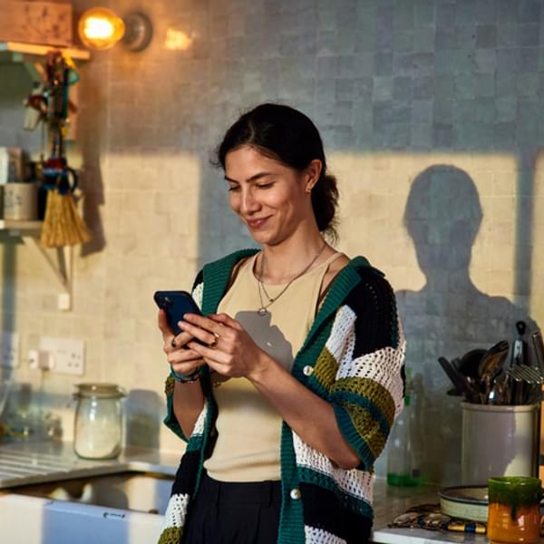 Happy woman using phone in kitchen.