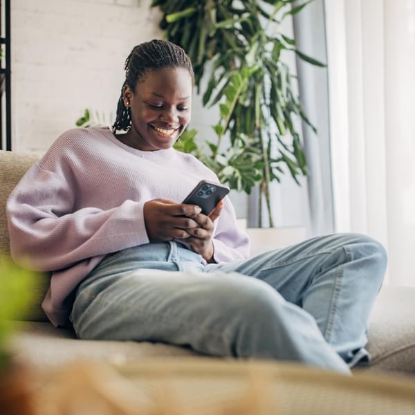 Cheerful woman using smartphone at home reacting to limited-time offer on an e-commerce platform.