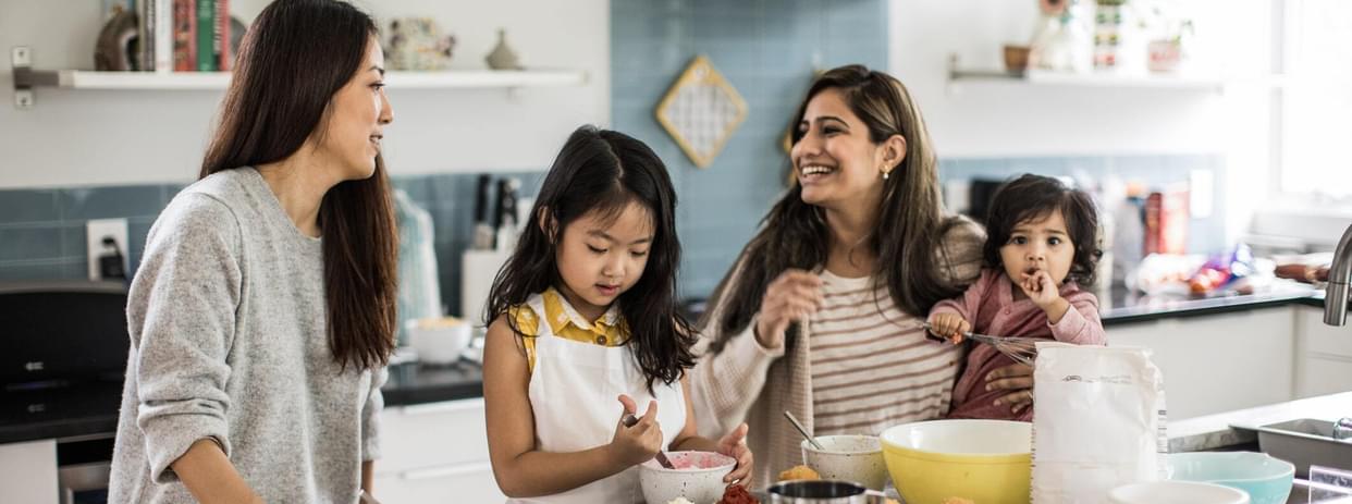 2 mothers with children makings cupcakes in energy-efficient kitchen