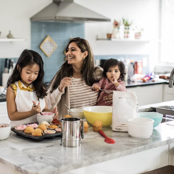 2 mothers with children makings cupcakes in energy-efficient kitchen