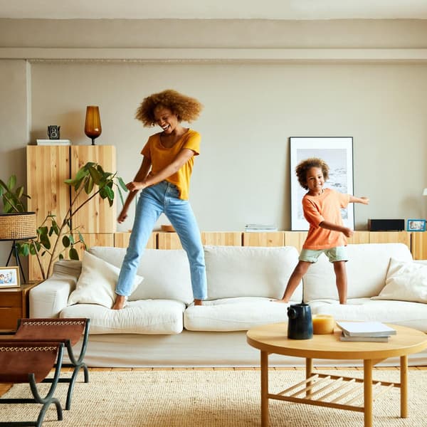 Happy mother and son dancing on sofa at home