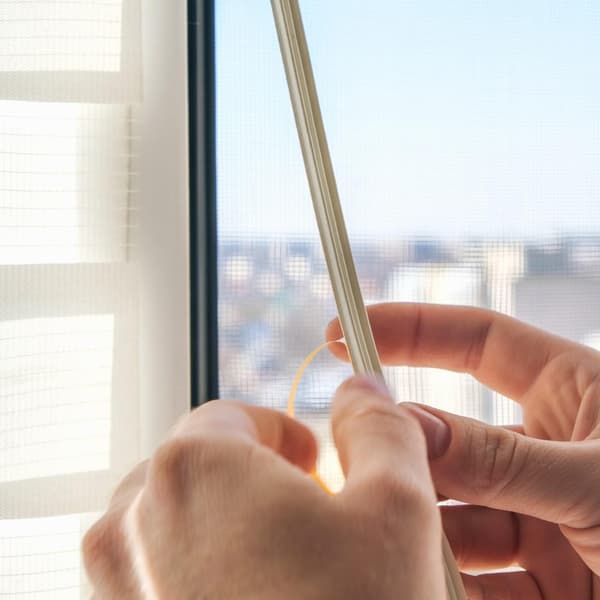 The man wipes the window frame with a degreaser and glues a sealing rubber tape on it for noise insulation, wind protection, weather protection